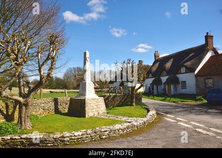 Kriegsdenkmal und strohgedeckte Hütten im Dorset-Dorf von Tarrant Monkton Stockfoto