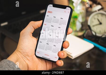 Kharkov, Ukraine - 27. April 2021: Man hält das Apple iPhone 12 mit Kalender-App auf dem Bildschirm, 2021 Kalender in Nahaufnahme auf dem Bildschirm Stockfoto