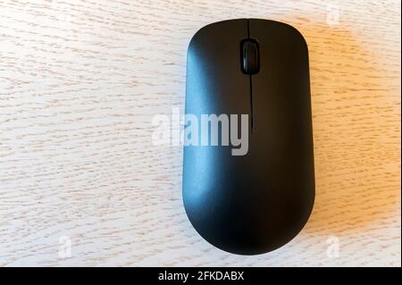 Schwarze kabellose Computermaus auf Holztisch Draufsicht Stockfoto