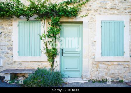 Fassade eines provenzalischen Hauses mit hölzernen Fensterläden und Baum Stockfoto