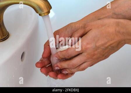 Nahaufnahme der Hände, die sich unter dem Wasserstrahl waschen Tippen Sie auf Stockfoto