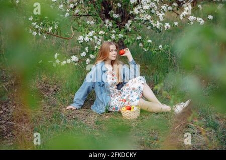 Eine junge Frau in einer blauen Denim-Jacke sitzt auf einer Lichtung. Stockfoto