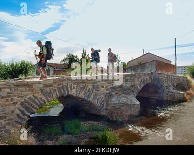 Drei Pilger auf der Puente de la Molinera, einer römischen Brücke auf dem Weg nach Santiago de Compostela beim Betreten von Astorga, Spanien, 16. Juli 2010 Stockfoto