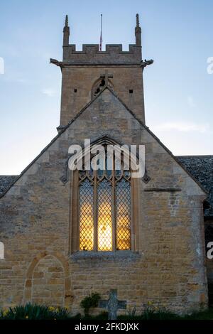 Durch das Fenster der St. Peter's Church, Willersey, Cotswolds, Gloucestershire, England, sticht das Licht des Sonnenaufgangs Stockfoto