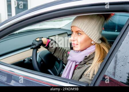 MINSK. WEISSRUSSLAND - JANUAR 2021: Eine schöne Frau schaut aus dem Fenster eines Elektroautos. Stockfoto