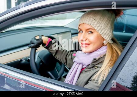 MINSK. WEISSRUSSLAND - JANUAR 2021: Eine schöne Frau schaut aus dem Fenster eines Elektroautos. Stockfoto