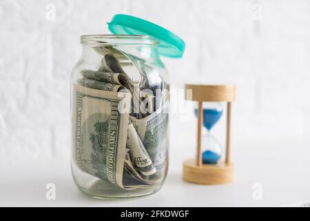 Faltet Geld in einem Glas auf einem weißen Holzhintergrund. Der Ort des Hintergrundbildes für Text. Stockfoto