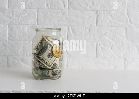 Faltet Geld in einem Glas auf einem weißen Holzhintergrund. Der Ort des Hintergrundbildes für Text. Stockfoto