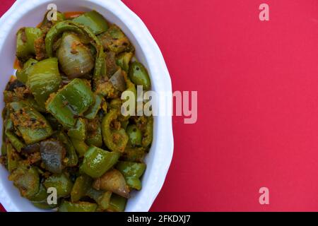 Köstliches Paprika- oder Paprikaschote-Paprikaschote. Mit Zwiebeln gebraten, indische asiatische Beilage. Auf rotem Hintergrund Stockfoto