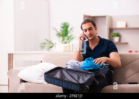 Junger Mann, der sich zu Hause auf die Reise vorbereitet Stockfoto