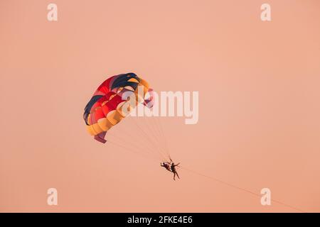 Parasailers Fliegen Auf Buntem Fallschirm Bei Sonnenuntergang Oder Sonnenaufgang Himmel. Aktiver Hobby Stockfoto