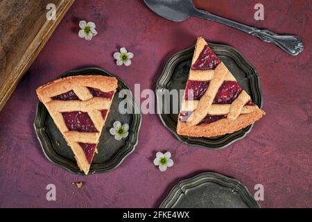 Tortenscheiben mit dem Namen „Linzer Torte“, einem traditionellen österreichischen Shortcake-Gebäck mit Fruchtkonserven und in Scheiben geschnittenen Nüssen im Gitterdesign Stockfoto