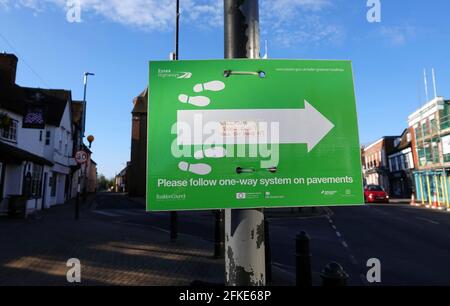 BILLERICAY, VEREINIGTES KÖNIGREICH - 20. Apr 2021: Ein grünes Schild des rates mit einem Pfeil und Fußabdrücken, das die Öffentlichkeit anweist, einer Einbahnstraße zu folgen Stockfoto