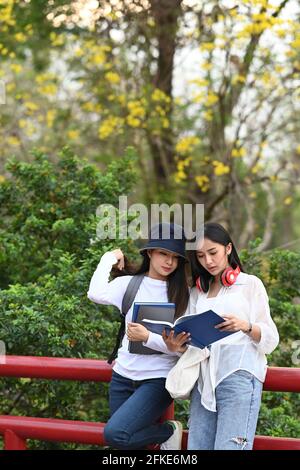 Zwei asiatische Universitätsstudenten sprechen über Prüfungsergebnisse und stehen zusammen auf dem College-Campus. Stockfoto