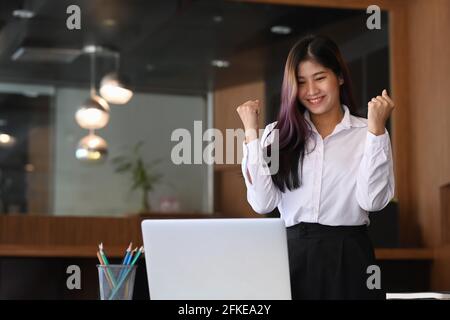 Lächelnde Geschäftsfrau, die im Büro steht und Erfolge feiert. Stockfoto