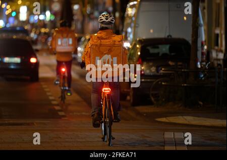 Köln, Deutschland. April 2021. Mitarbeiter des Lieferservice fahren Fahrräder, um bestellte Lebensmittel an Kunden zu liefern, nachdem die Ausgangssperre um 21:00 Uhr beginnt. Quelle: Henning Kaiser/dpa/Alamy Live News Stockfoto