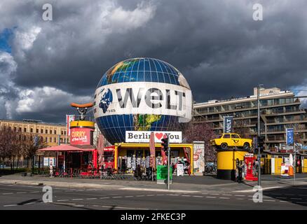 Fastfood-Stall mit Wurstwaren, Ballonfahrt mit Festungsballon und gelbes Trabi-Auto. Sehenswürdigkeiten in Mitte, Berlin, Deutschland. Stockfoto