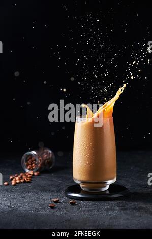 Iced Coffee with Splash in Tall Glass on Dark Background. Konzept Erfrischendes Sommergetränk. Stockfoto
