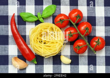 Auswahl an Pasta-Zutaten: Tagliatelle, Kirschtomaten, Knoblauch, Chili und frische Basilikumblätter Stockfoto