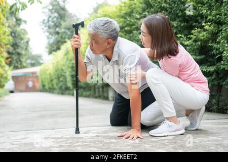 Asiatischer älterer Mann fiel zu Hause im Hinterhof durch Myasthenie (Muskelschwäche) und die Krankenschwester kam, um Unterstützung zu helfen. Konzept der alten elderl Stockfoto