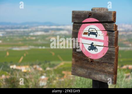 Schild, das den Durchgang von Kraftfahrzeugen auf einem Holzbrett mit Landschaft im Hintergrund gemalt untersagt Stockfoto