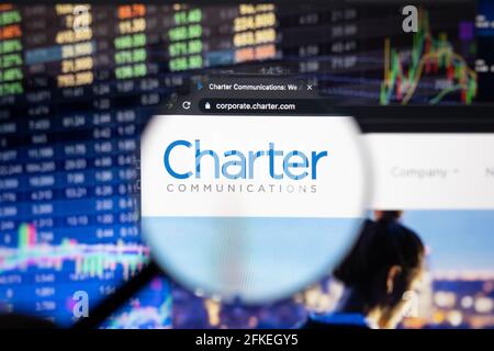 Logo des Unternehmens Charter Communications auf einer Website mit verschwommenen Börsenentwicklungen im Hintergrund, die auf einem Computerbildschirm zu sehen sind Stockfoto