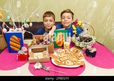 Zwei Jungen zeigen ihre eigenen handgefertigten Osterdekorationen. Bemalte Eier, Applikationen, dekorierte Kekse und hausgemachte Hühner. Stockfoto