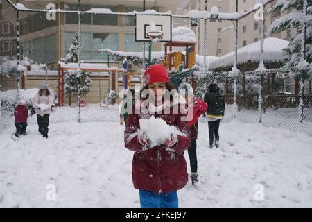 Mädchen spielen mit Schnee an einem verschneiten Tag auf dem Spielplatz Stockfoto