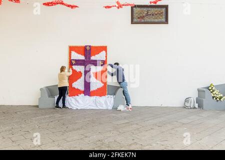 Tamaimo, Teneriffa, Kanarische Inseln. Mai 2021. Mit Blumen geschmückte Kreuze für die jährliche Feier des Kreuzweges auf der Plaza del Iglesia in Tamaimo, Santiago del Teide. Hergestellt von der Associacón de Vecinos de Tamaimo. Amelia Barros und Rafael Manzano hängen das Kreuz auf. Stockfoto