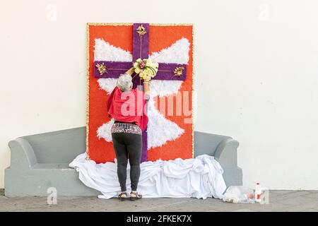 Tamaimo, Teneriffa, Kanarische Inseln. Mai 2021. Mit Blumen geschmückte Kreuze für die jährliche Feier des Kreuzweges auf der Plaza del Iglesia in Tamaimo, Santiago del Teide. Hergestellt von der Associacón de Vecinos de Tamaimo. Mari Carmen Rolo setzt Blumen auf das Kreuz. Stockfoto