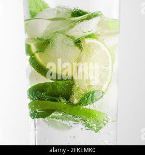 Mojito Cocktail in einem Glas auf weißem Hintergrund Nahaufnahme kaltes leichtes Getränk. Limettenscheiben, Minzblätter und Eiswürfel. Stockfoto