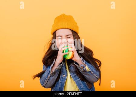 Ein Mädchen in einem mehrfarbigen Hemd hält ein mehrfarbiges, slinky Spielzeug In ihren Händen Stockfoto