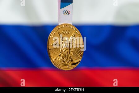 25. April 2021 Tokio, Japan. Goldmedaille der XXXII. Olympischen Sommerspiele 2020 in Tokio auf dem Hintergrund der russischen Flagge. Stockfoto
