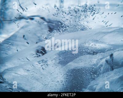 Makro-Nahaufnahme mit transparenter Eisstruktur. Ein Stück Eis mit Glühbirnen. Makroansicht des Eiswürfels. Stockfoto