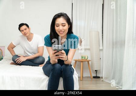 Asiatischer Mann misstrauisch Gefühl meiner Frau Anomalie in Smartphone-Nutzung und seine Frau ignoriert ihn und nutzt das Smartphone alle Zeiten. Konzept der rela Stockfoto