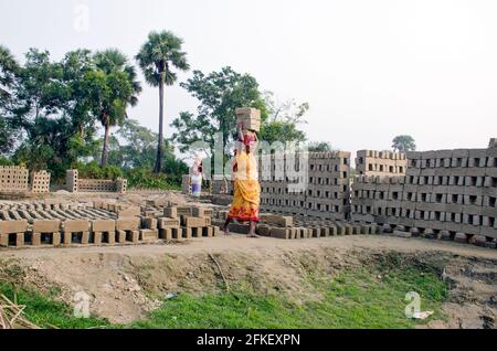 Bild eines Ziegelofens im abgelegenen Hooghly-Viertel. Erwachsene Arbeiter arbeiten hart daran, die rohen Ziegelsteine im Ofen zum Backen zu arrangieren. Stockfoto