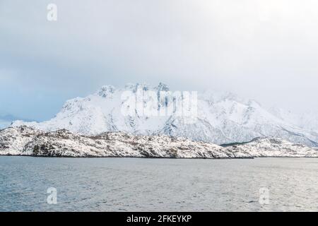 Eine Winterlandschaft, die das ruhige Wasser des Norwegischen Meeres umschließt. Ruhig und angenehm, zieht sich die Atmosphäre über das Meer und setzt eine beruhigende Aura ein Stockfoto
