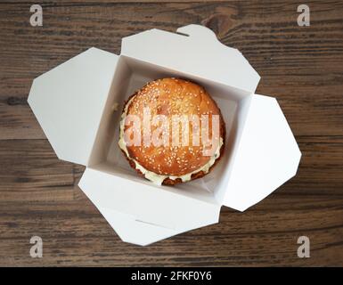 Frischer, leckerer Burger in einer Papierkiste auf einem Holztisch, Draufsicht, selektiver Fokus Stockfoto
