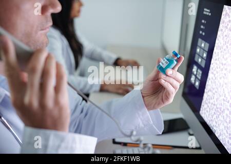 Arzt, der Telefonat führt, um die Nebenwirkungen von neuen zu besprechen Impfstoff gegen Coronavirus Stockfoto