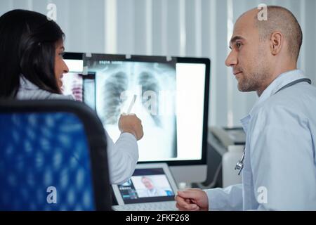 Ein Team von Pneumologen diskutiert die Röntgenaufnahme des Patienten in Brust und Lunge Mit Coronavirus auf dem Computerbildschirm Stockfoto