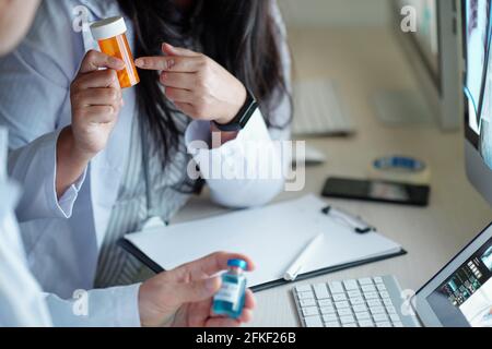 Ärzteteam, das Medikamente oder Nahrungsergänzungsmittel für kranke Patienten auswählt Beim Sitzen am Schreibtisch im Krankenhaus Stockfoto