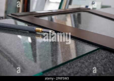 Ein Messer zum Schneiden von Glas und eine Winkelstange liegen Auf der Glasscheibe in einer Glasfabrik Stockfoto