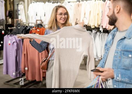 Ein Mann und eine Frau, die beim Einkaufen neue Kleidung wählen Stockfoto