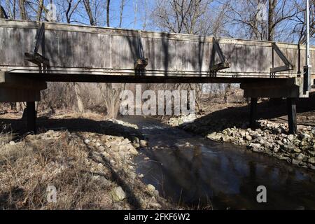 Alte Holzbrücke über einen kleinen Bach im Frühjahr Stockfoto