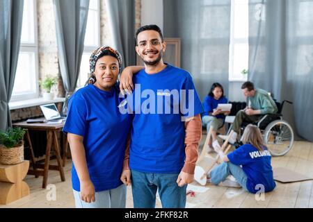 Eine Gruppe glücklicher junger interkultureller Menschen in blauen T-Shirts Posiert für ein Foto Stockfoto