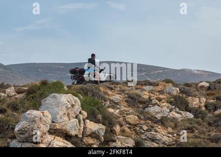 Paros Bay, Griechenland - 28. September 2020: Mann auf weißen Quad-Bikes auf einem Landweg. Schotterstraße entlang der Küste. Stockfoto