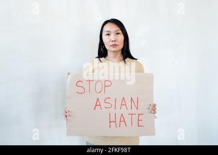 Asiatische Frau mit einem Papier, das Protest gegen nationale Diskriminierung ankündigt Stockfoto
