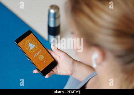 Junge Frau nutzt mobile Anwendung, wenn sie zu Hause Yoga praktiziert Stockfoto
