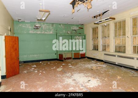 Ein leerer Raum in einer alten verlassenen Schule. Herabfallende Decke und Ablagerungen auf dem Boden. Dieses Zimmer war die Bibliothek. Stockfoto