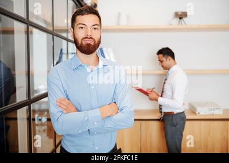 Porträt eines gutaussehenden, selbstbewussten bärtigen Unternehmers, der die Arme kreuzt und schaut Bei der Kamera Stockfoto